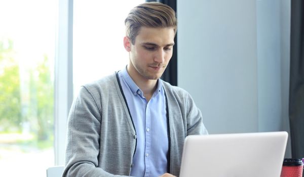 Young modern business man working using laptop while sitting in the office