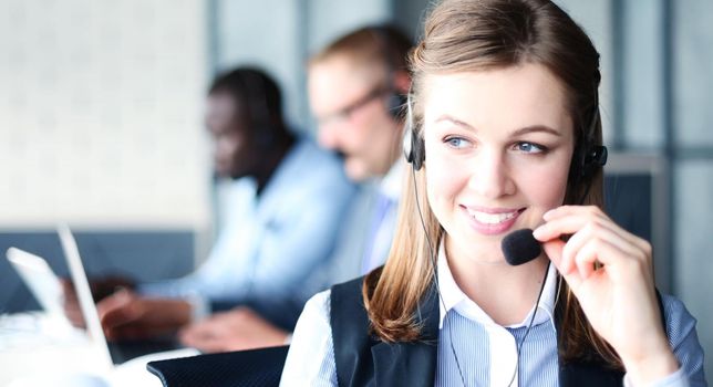 Portrait of call center worker accompanied by her team. Smiling customer support operator at work.