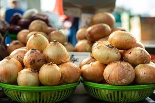 Two heaps of white onion bulbs in green plastic baskets are being sold at the market.