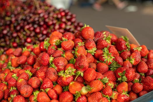 Close-up of heap of many fresh and organic tasty strawberries for sale at the farmers market in the summer. Summer harvest of strawberries.