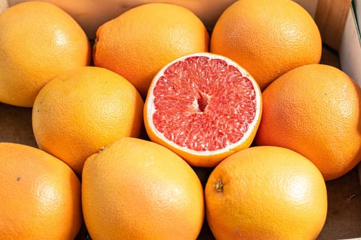 Close up picture with a lot of fresh orange and red grapefruits in the sunshine.