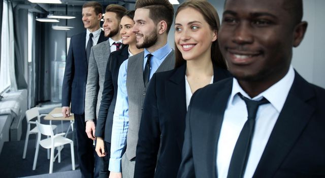 Happy smiling business team standing in a row at office.