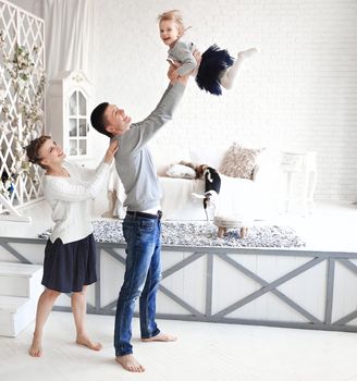 mother and father playing with his baby daughter in the bedroom.