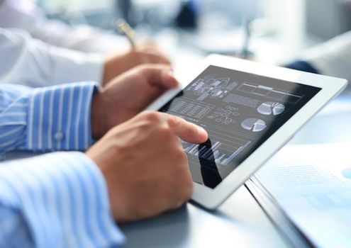 Cropped shot of a group of businesspeople looking at graphs on digital tablets