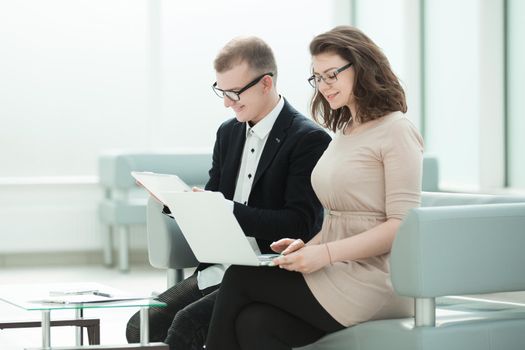 business colleagues use gadgets sitting in the office hall. photo with copy space