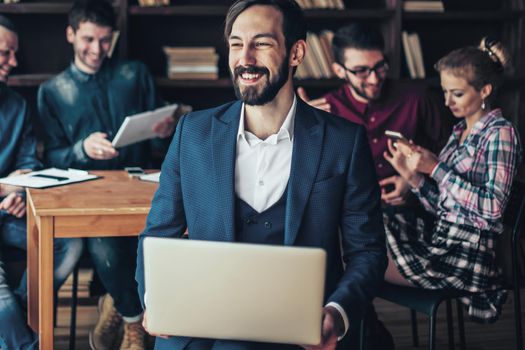 successful employee of the firm with a laptop and a business team discussing the current problems of the company