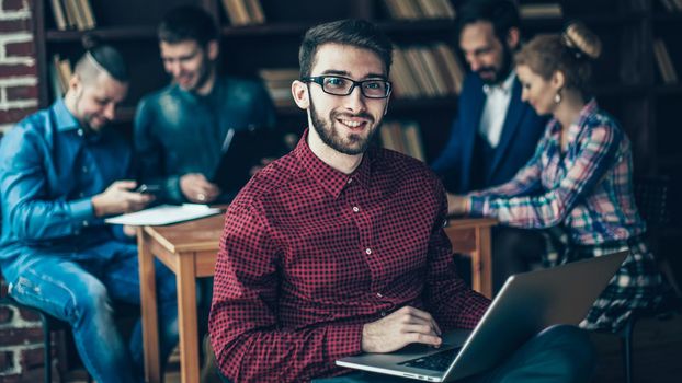in the foreground the successful employee of the company with laptop on the background of business team