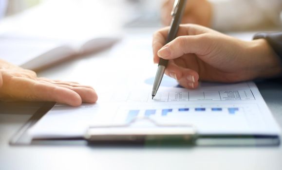 Unrecognizable business person analyzing graphs and taking notes