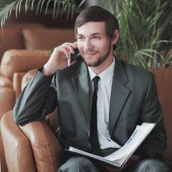 closeup. Businessman sitting in a business center reading documents while having a phone call