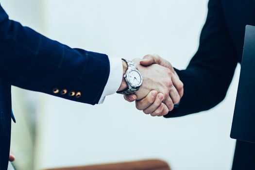 in the foreground - handshake of business partners on the background of the office