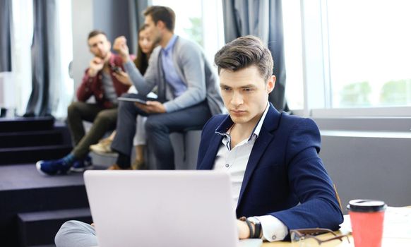 Young smart people are using gadgets while working hard in the modern office. Young man working on his laptop.