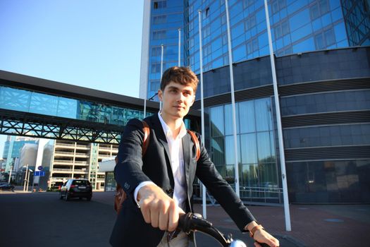 Confident young businessman walking with bicycle on the street in town.