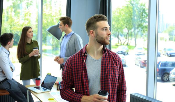 Happy attracive young businessman drinking coffee in office.