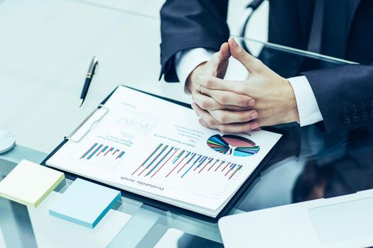 closeup of a businessman ponders the financial policy of the company sitting behind a Desk in the office