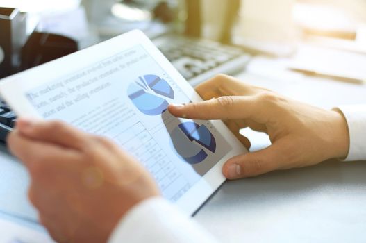 Business person analyzing financial statistics displayed on the tablet screen