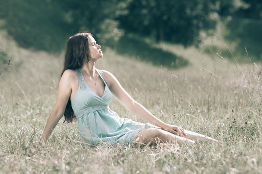 beautiful young woman sitting in forest glade on summer day.photo with copy space