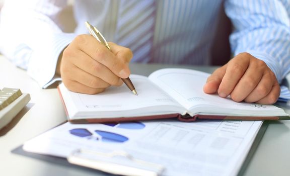 Businesswoman makes a note in notebook.