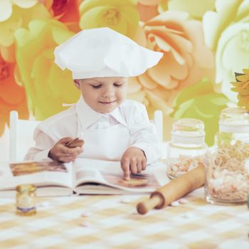 happy little boy with a book chef preparing Breakfast in the kit