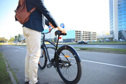 Confident young businessman walking with bicycle on the street in town.