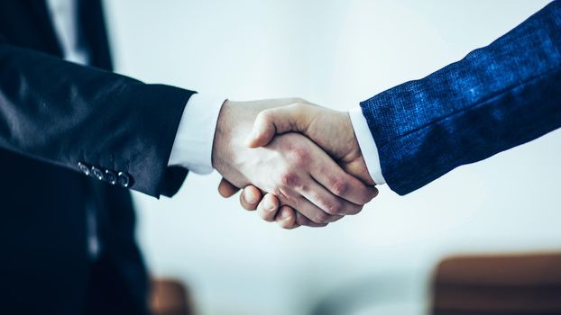 closeup of handshake of business partners on the background of bright office.