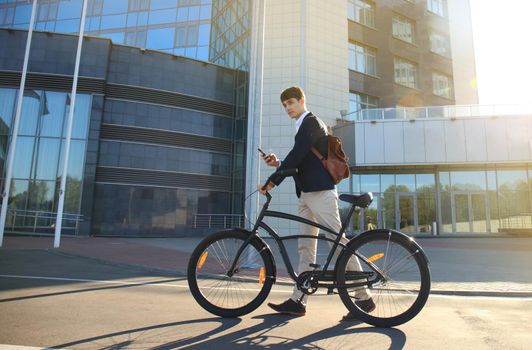 Confident young businessman walking with bicycle on the street in town.