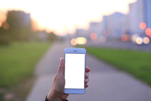 Closeup of female hand holding modern smartphone with blank screen, display at night city.