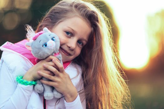 little girl hugging a favorite stuffed animal - a cat for a walk in the Park on a Sunny day.the photo has a empty space for your text