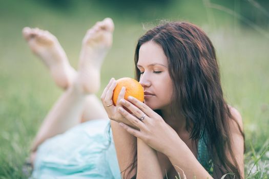 cute girl with orange on the background of nature. photo with copy space