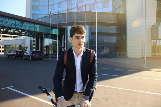 Confident young businessman walking with bicycle on the street in town.