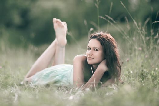 cute young woman lying in a forest glade . photo with copy space