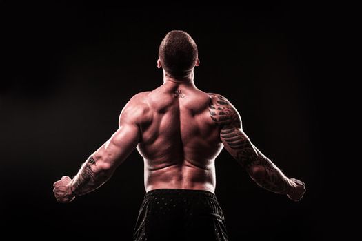 rear view. male bodybuilder looking at copy space.isolated on black background