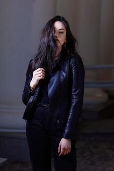 stylish girl in a leather jacket and evening makeup, standing on the street of the city at night