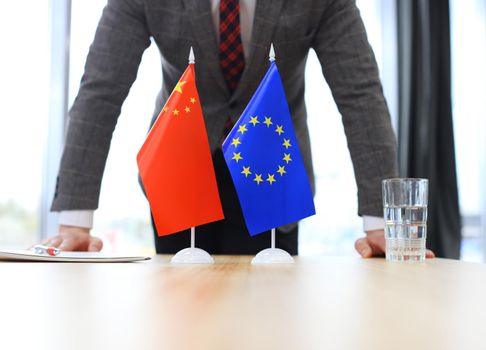 Chinese flag and flag of European Union with businessman near by