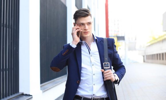 Young urban businessman professional on smartphone walking in street using mobile phone