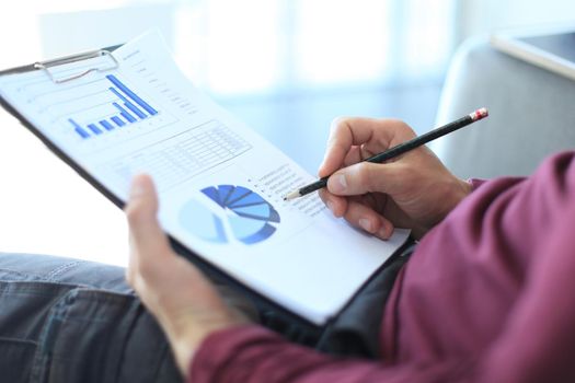 Business man working at office with graph data documents on his desk.