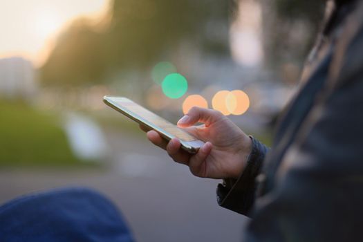 Closeup of female hand holding modern smartphone with blank screen, display at night city.