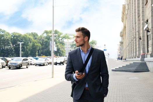 Young urban businessman professional on smartphone walking in street using mobile phone.