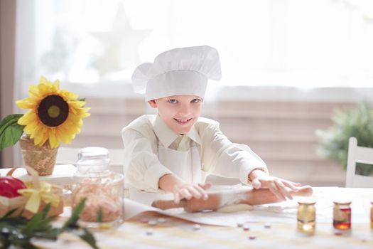 little boy in a chef's hat rolls the dough.Hobbies and interests