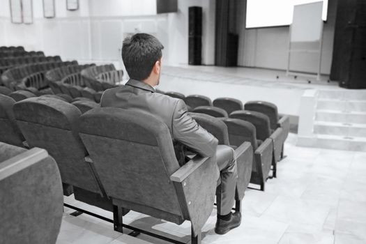 businessman sitting in an empty conference hall. business and education