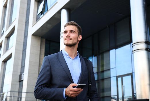 Young urban businessman professional on smartphone walking in street using mobile phone.