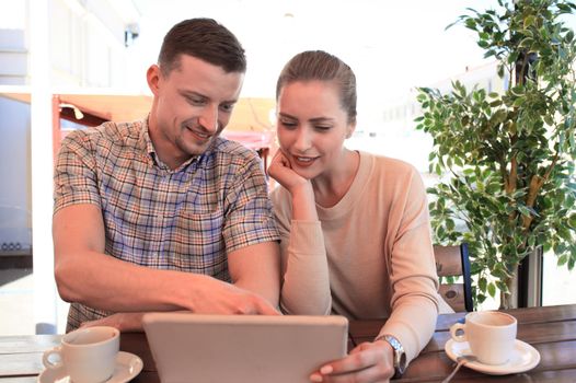 Flirting couple in cafe using digital tablet.