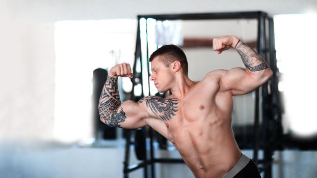 male bodybuilder performs exercises in front of a mirror . photo with copy space