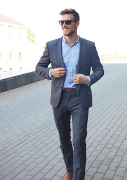 handsome stylish man in elegant suit and sunglasses in the street.