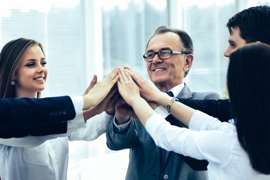 Happy business team celebrating victory at the office hands folded together in the form of a pyramid