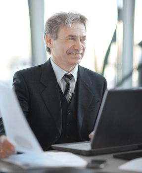 closeup. smiling senior businessman sitting at his Desk