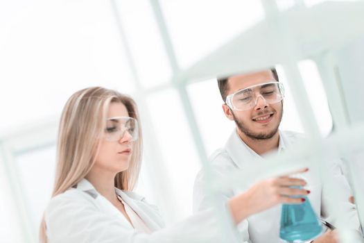 smiling scientist showing his colleague a flask of liquid. science and health