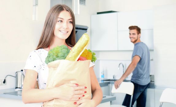 Young couple in the kitchen , woman with a bag of groceries shopping