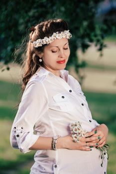 portrait of a cute pregnant woman with a bouquet of daisies . the concept of motherhood