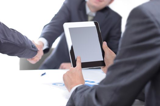 close up.businessman with a digital tablet on the background of a handshake of business partners