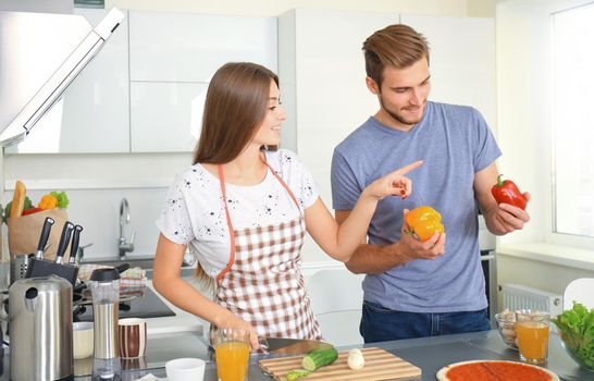 Portrait of happy young couple cooking together in the kitchen at home.